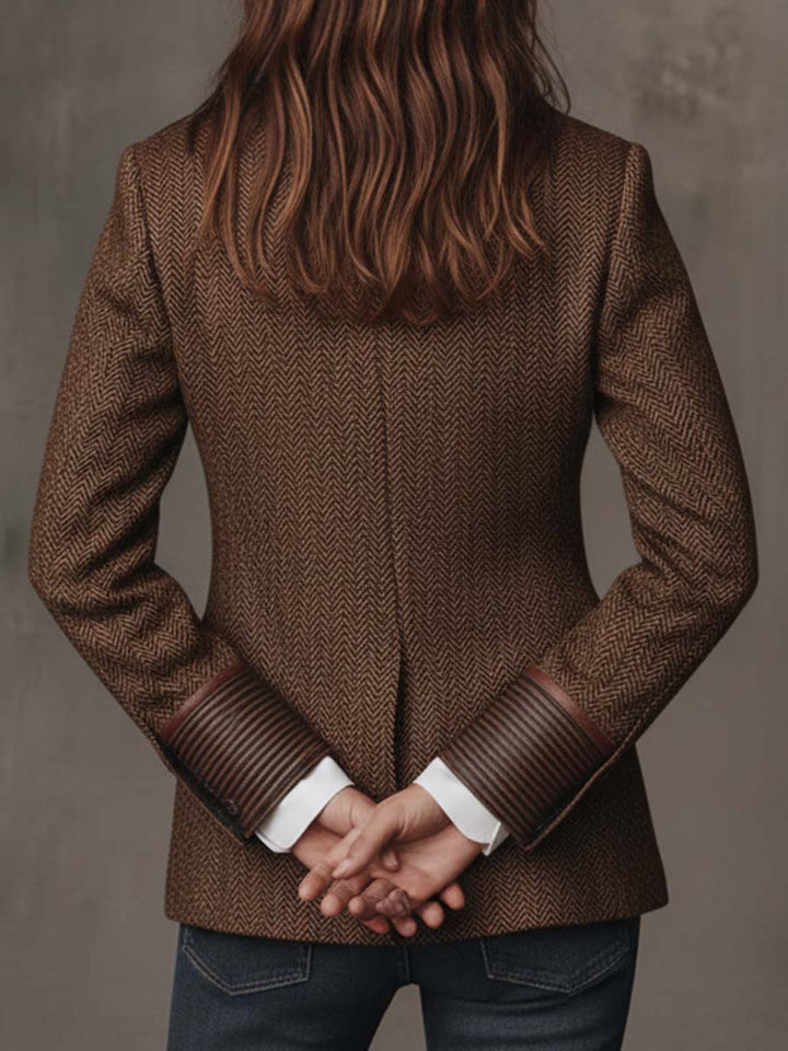 Back of the brown blazer with hands clasped behind and trimmed cuffs