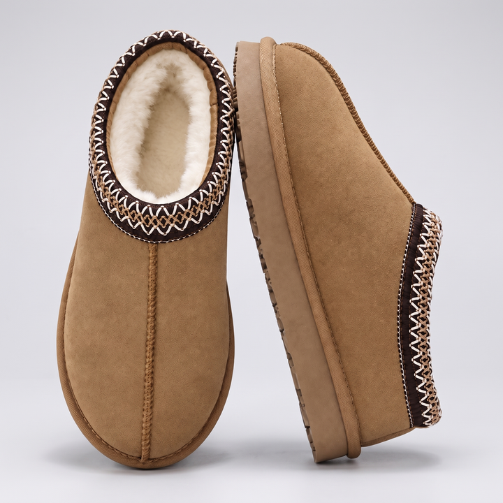 Pair of tan slippers with cream lining and embroidered collar, one standing on its side