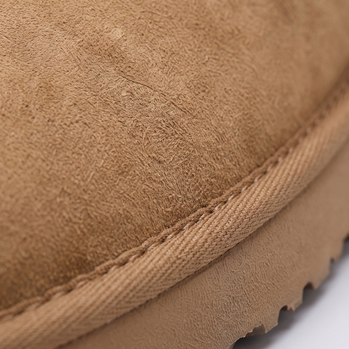 Close-up of the suede-look slipper upper, stitched seam and ridged sole edge
