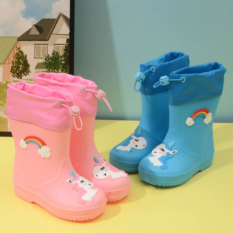 Pink and blue unicorn rain boots with drawstring cuffs on a yellow surface