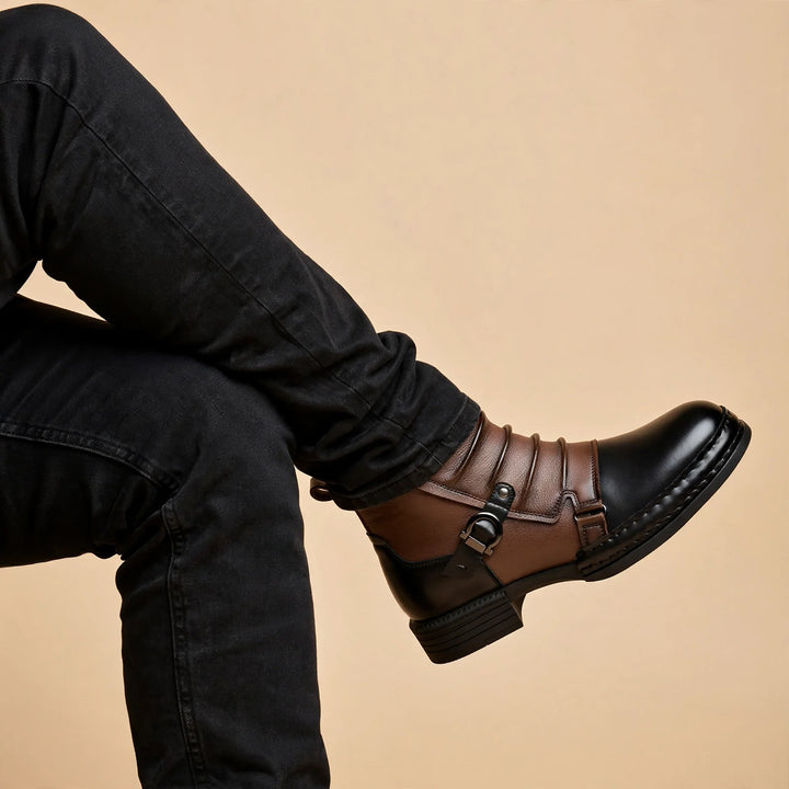 Seated man with crossed legs wearing the two tone ruched ankle boot with black jeans