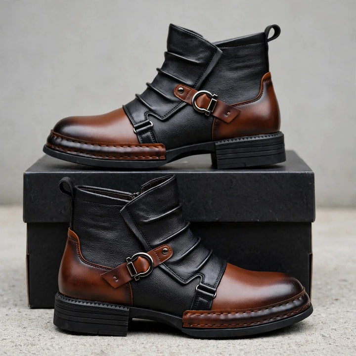 Pair of black and brown buckle strap boots displayed on a black box