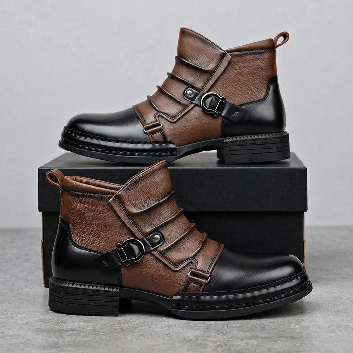 Pair of two tone ruched ankle boots stacked on a black shoebox with buckle straps