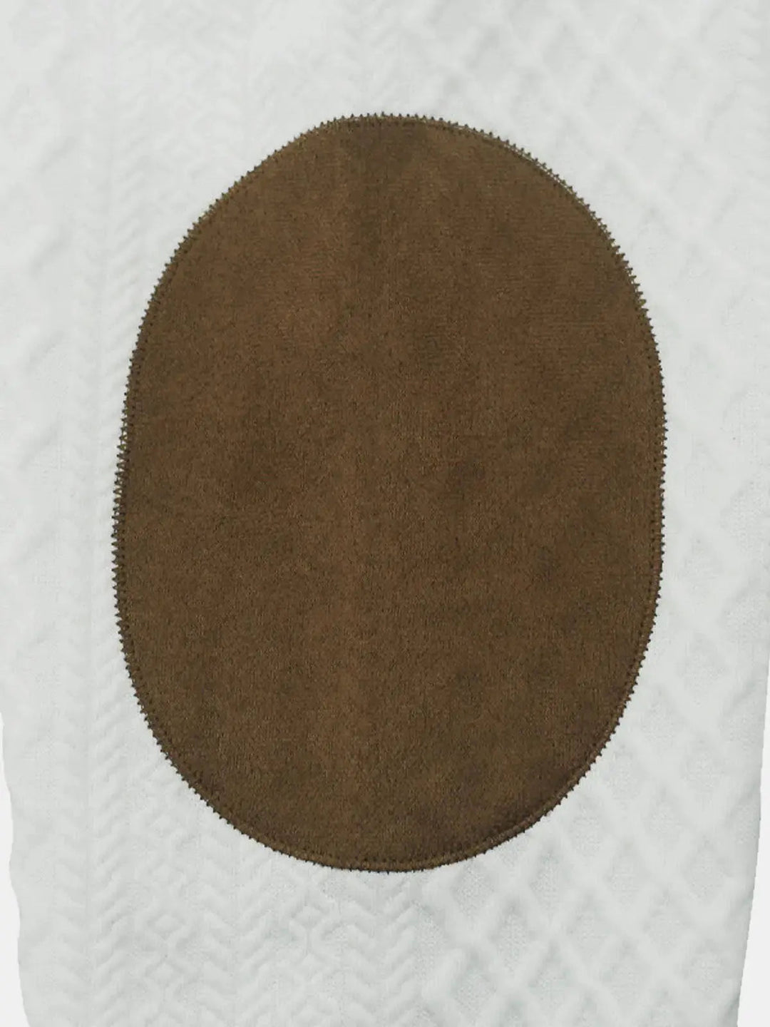 Close up of the brown oval elbow patch on the white cable knit sleeve