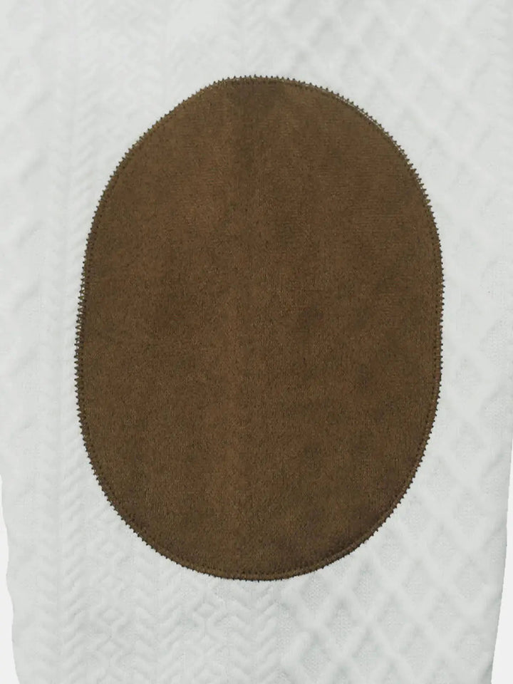 Close up of the brown oval elbow patch on the white cable knit sleeve