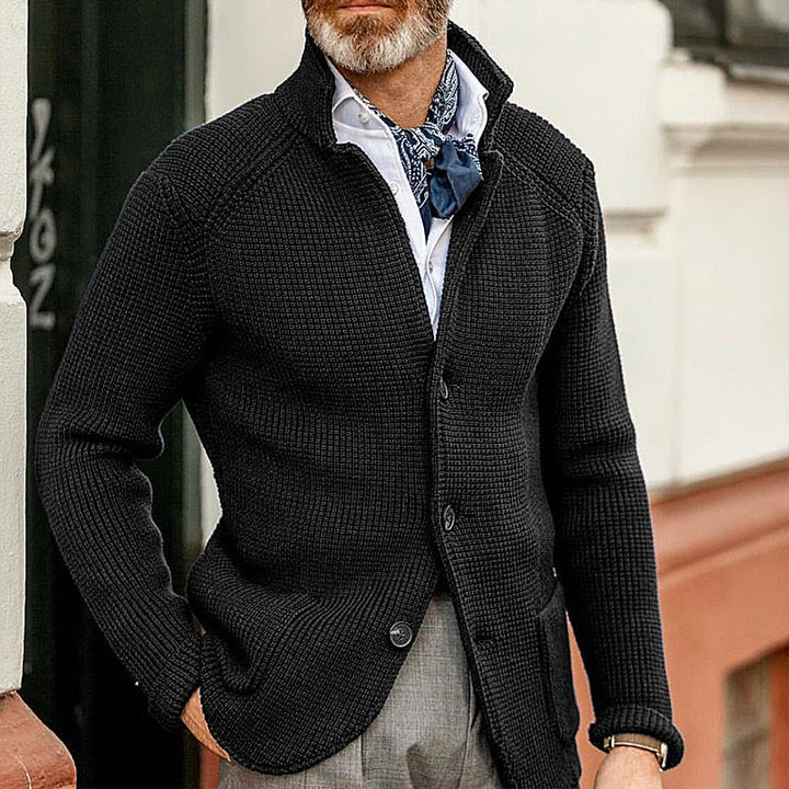 Black button up knit cardigan with stand collar worn over a white shirt