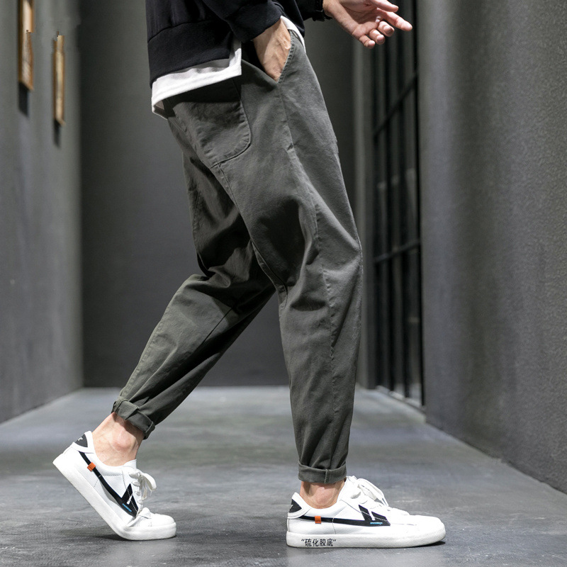 Olive tapered joggers in side view while walking, with white sneakers