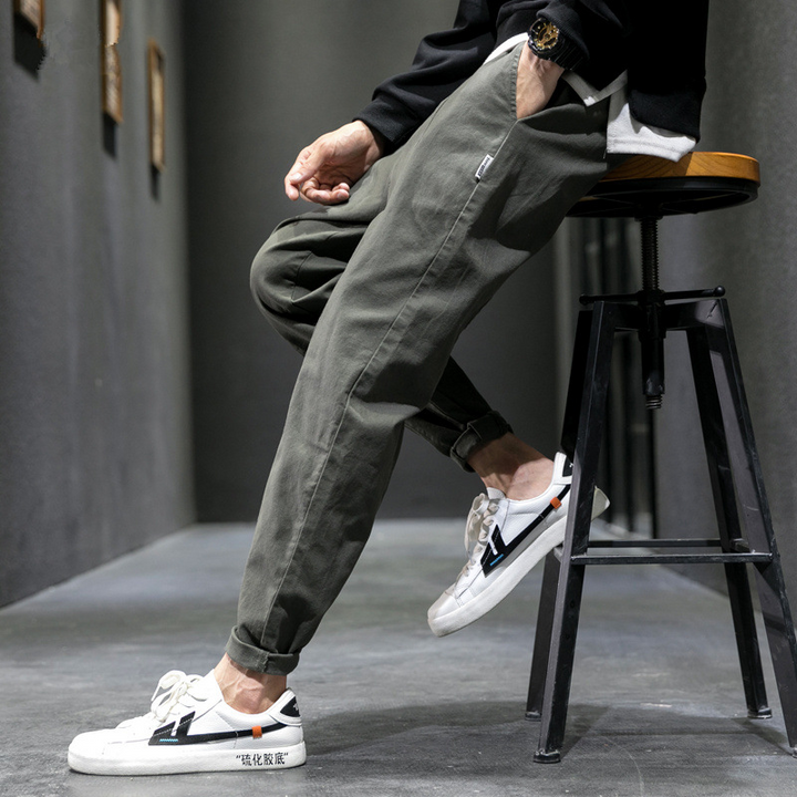 Olive cargo joggers worn while seated on a stool with black jacket