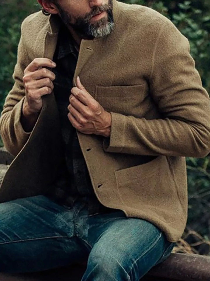 Model seated outdoors in the khaki blazer over a checked shirt