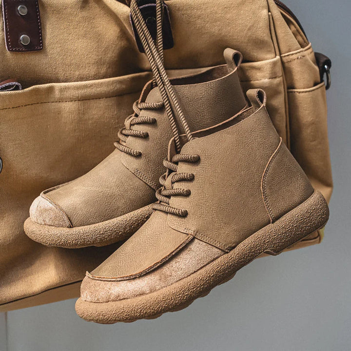 Close up of tan lace up ankle boots resting on a canvas bag