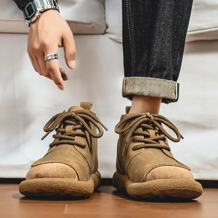 Tan lace up ankle boots worn with rolled jeans on a wooden floor
