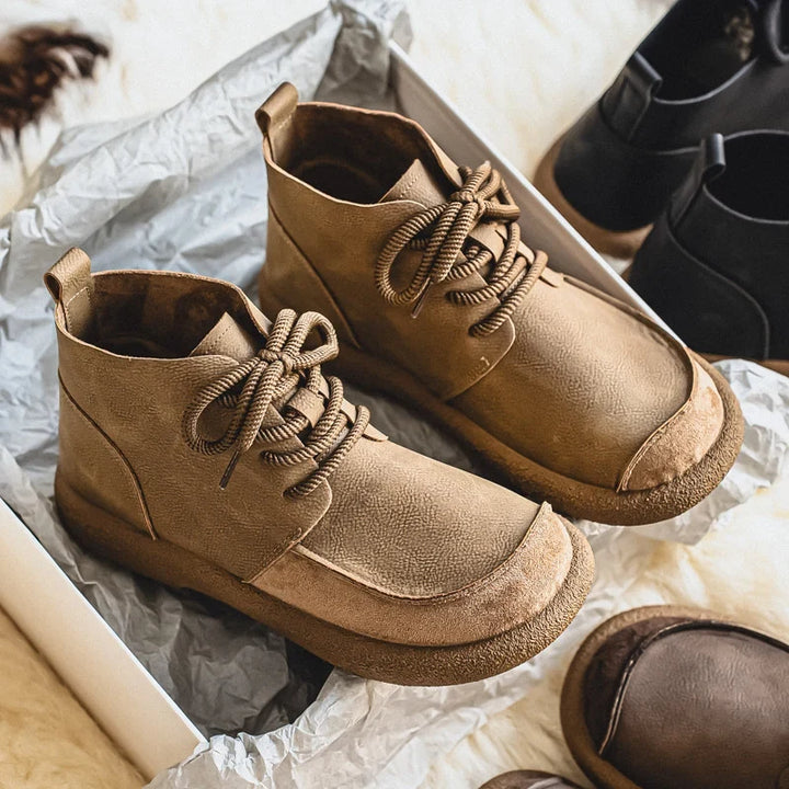 Pair of tan lace up ankle boots on silver paper