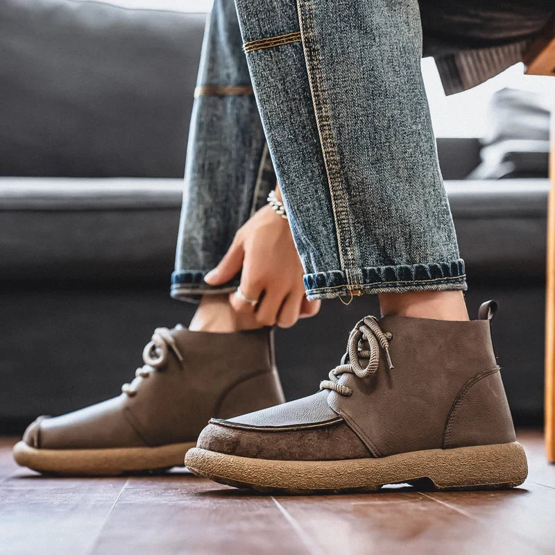 Taupe lace up ankle boots worn with jeans while tying the laces