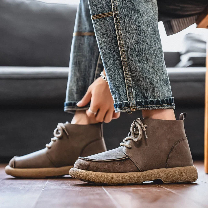 Taupe lace up ankle boots worn with jeans while tying the laces