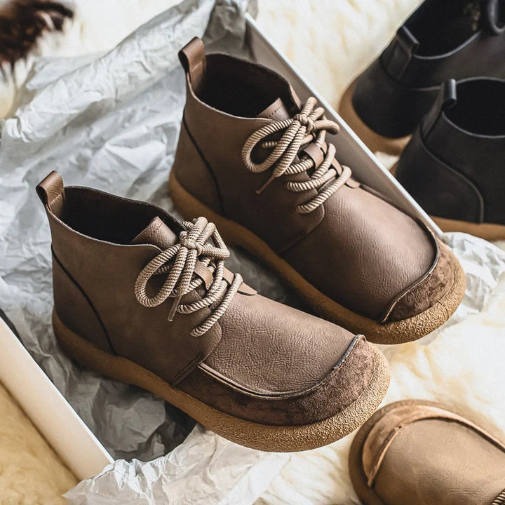 Pair of taupe lace up ankle boots on silver paper