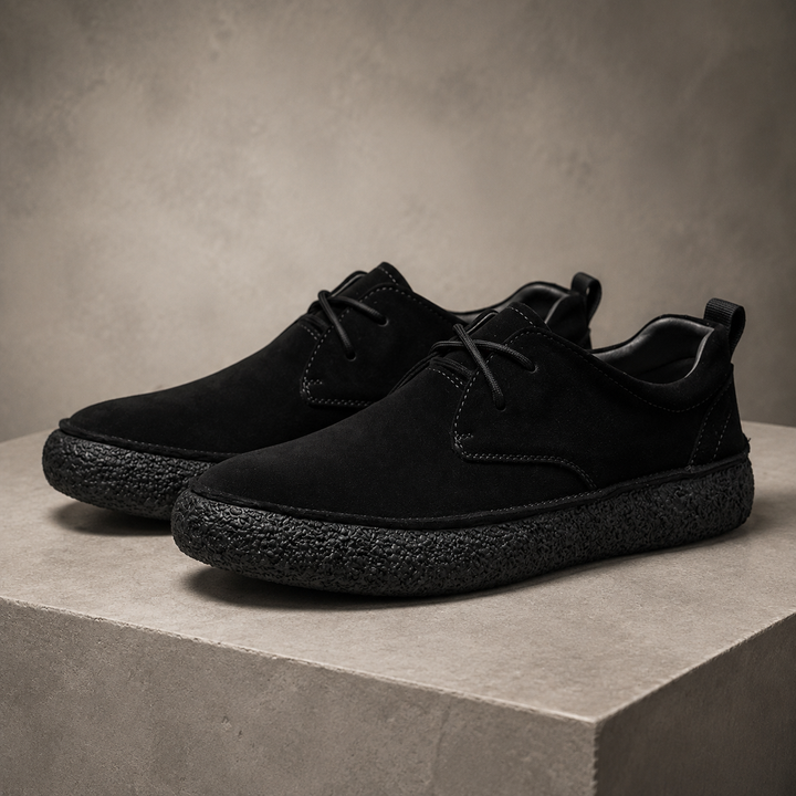 Pair of black suede look low top shoes with crepe sole on a block