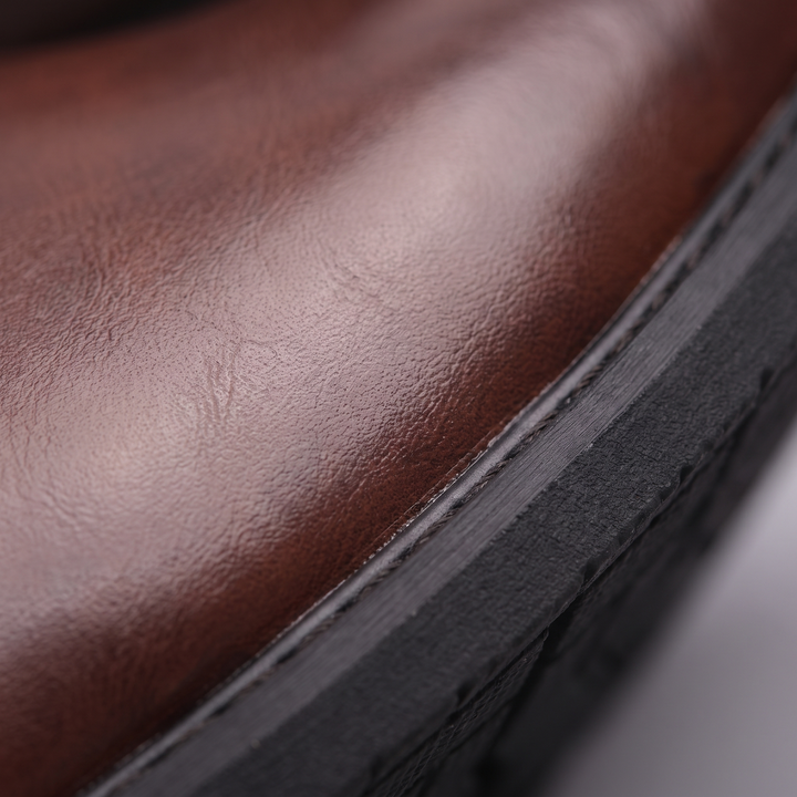 Close up of the polished finish and stitched welt edge on a dark brown boot