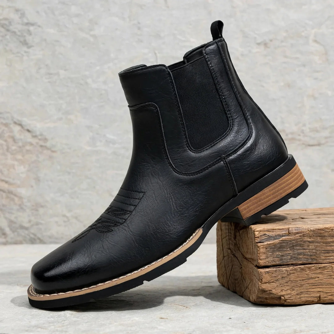 Black western stitched Chelsea boot with elastic side panel on a wooden block