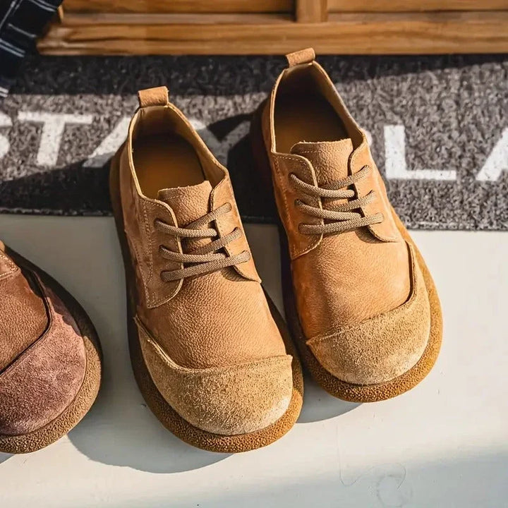 Pair of tan wide toe lace up shoes on a doormat