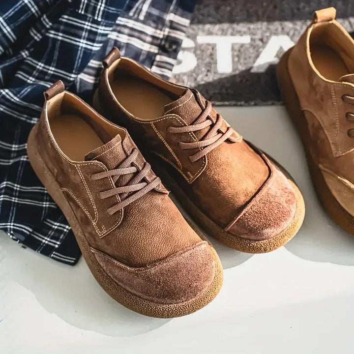 Tan wide toe lace up shoes angled on a checked cloth