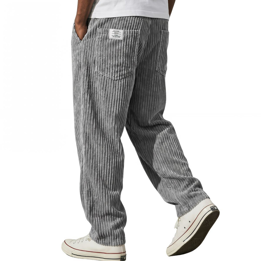 Gray corduroy pants in side walking view with white sneakers