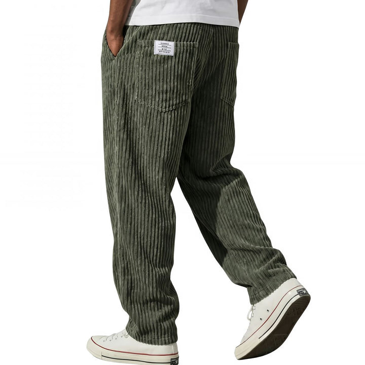 Dark green corduroy pants styled with white sneakers, side view