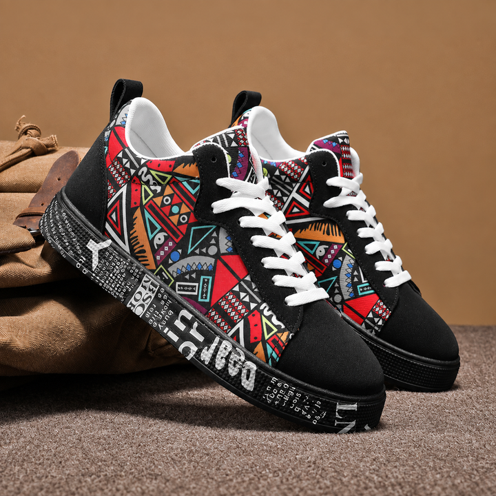 Pair of black graphic print low top sneakers resting on a canvas bag