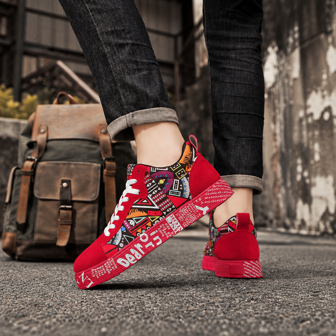 Red graphic print sneakers worn with dark jeans beside a leather backpack
