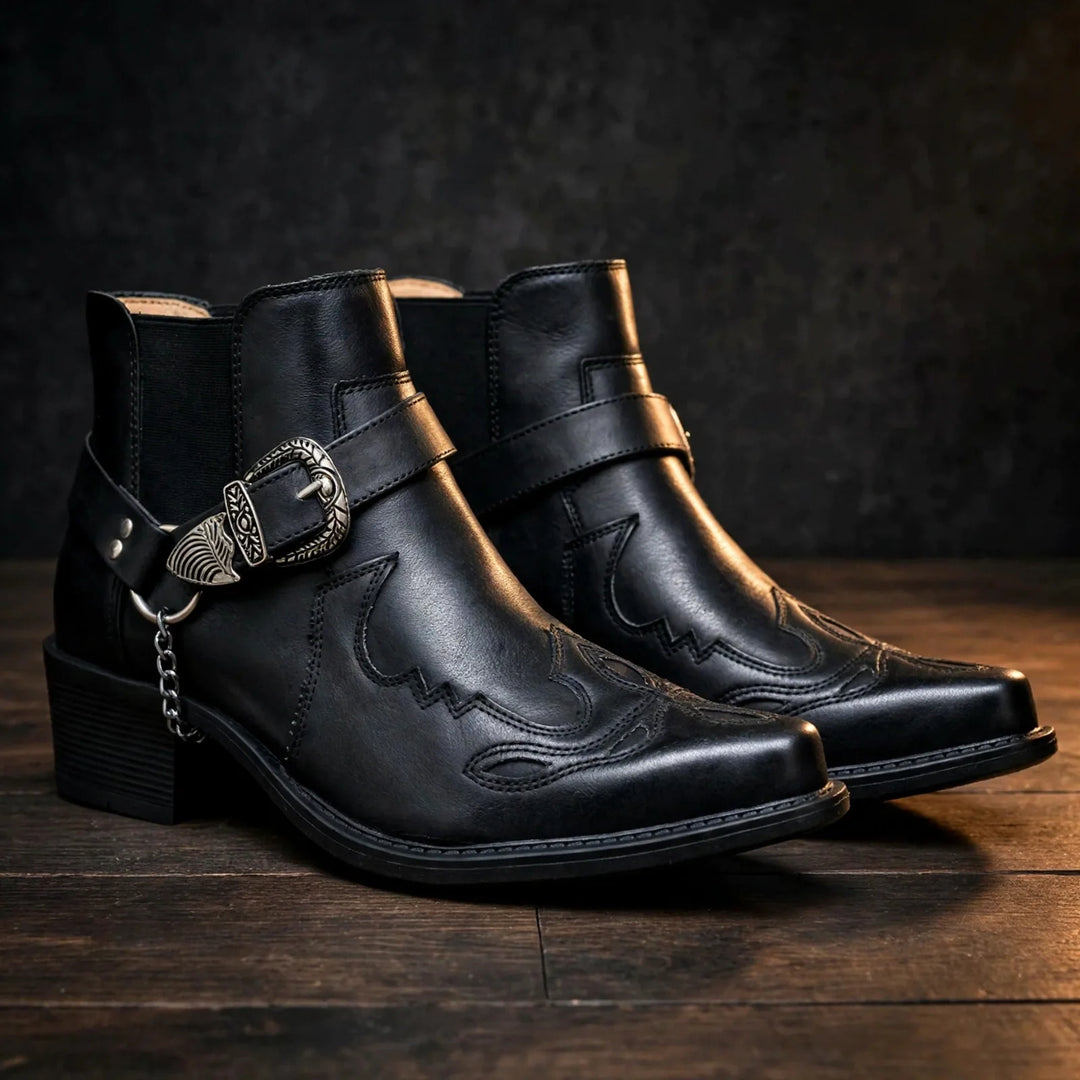 Pair of black cowboy ankle boots with pointed toe and harness strap