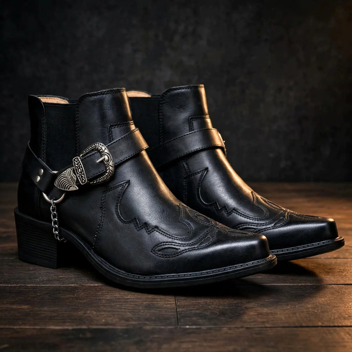 Pair of black cowboy ankle boots with pointed toe and harness strap