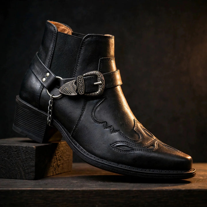 Black pointed toe cowboy ankle boot with harness buckle and chain, side view