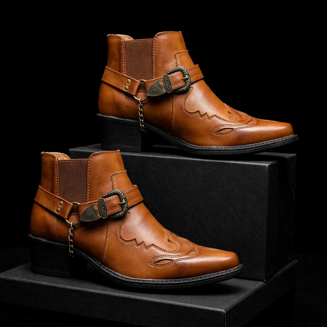 Two cognac cowboy ankle boots displayed on black blocks, showing stitched pattern