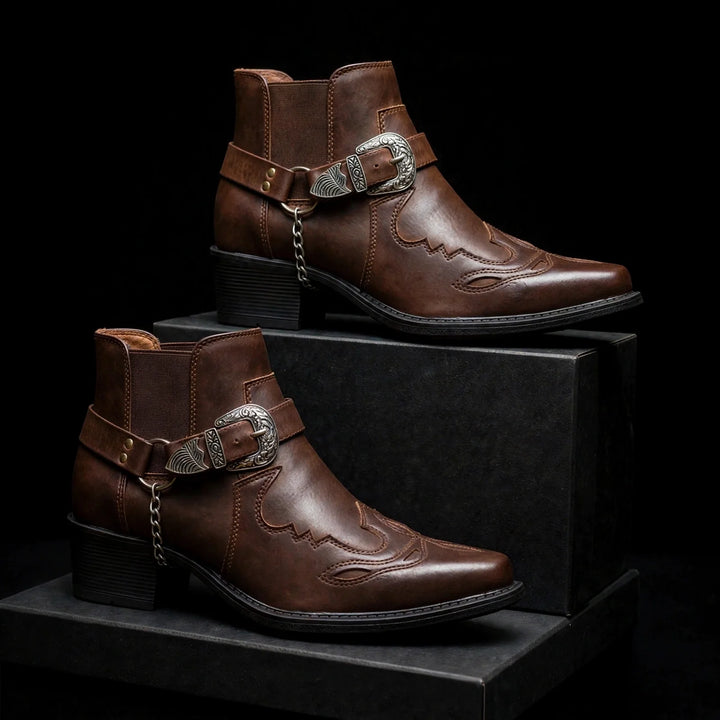 Two dark brown harness ankle boots displayed on black blocks