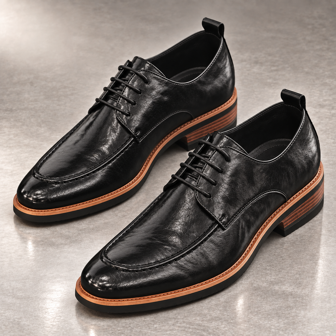 Pair of black derby shoes with apron toe and stacked heel on a gray floor