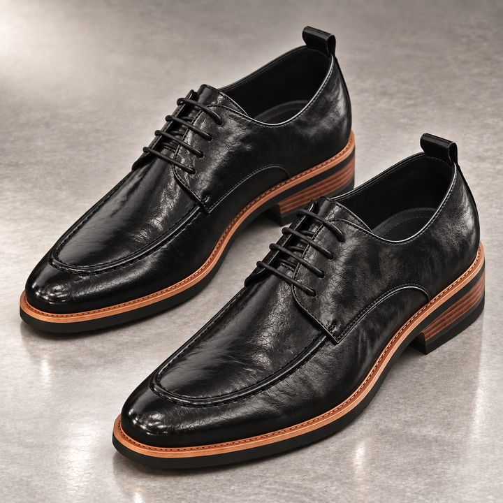 Pair of black derby shoes with apron toe and stacked heel on a gray floor