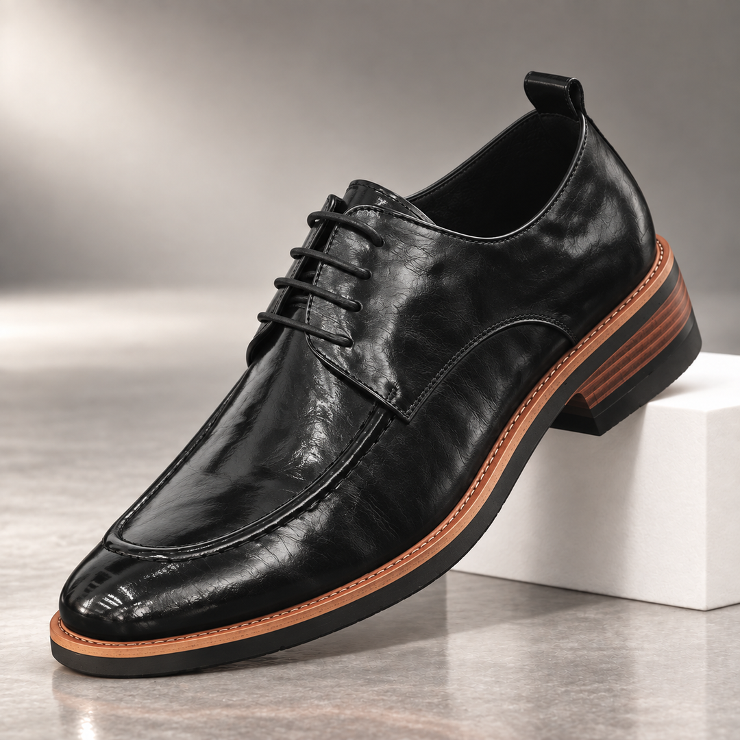 Black lace up derby shoe with apron toe and tan welt, side view on a block