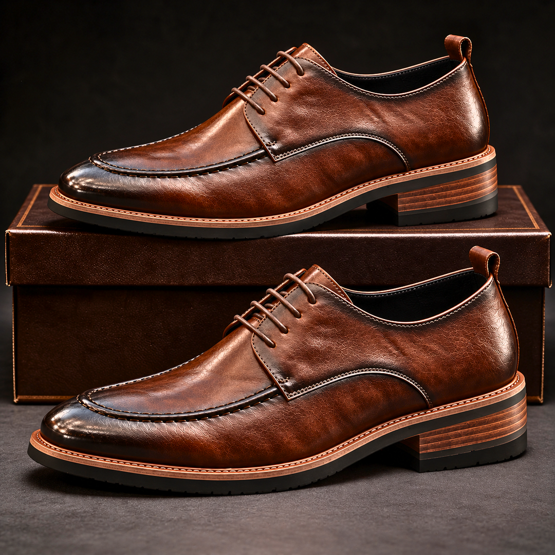 Brown burnished derby shoes stacked on a dark brown shoe box