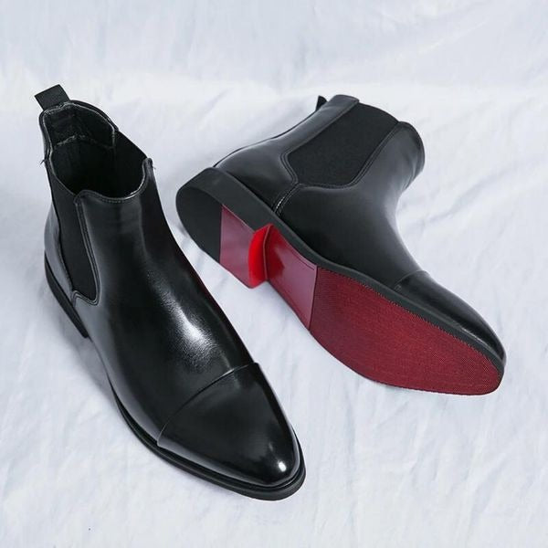 Pair of black dress chelsea boots, one standing and one turned to show the sole