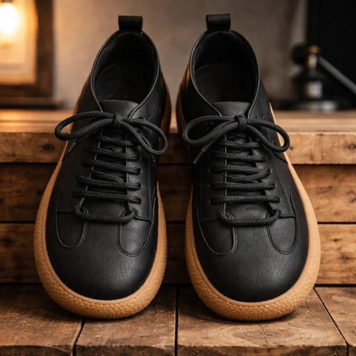 Pair of black wide toe lace up sneakers on a wooden shelf