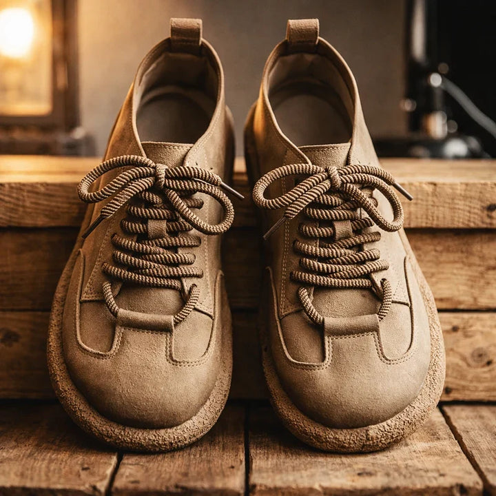 Pair of tan wide toe lace up sneakers on a wooden shelf