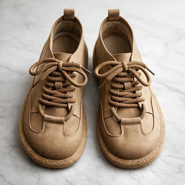 Tan wide toe lace up sneakers angled on a marble surface
