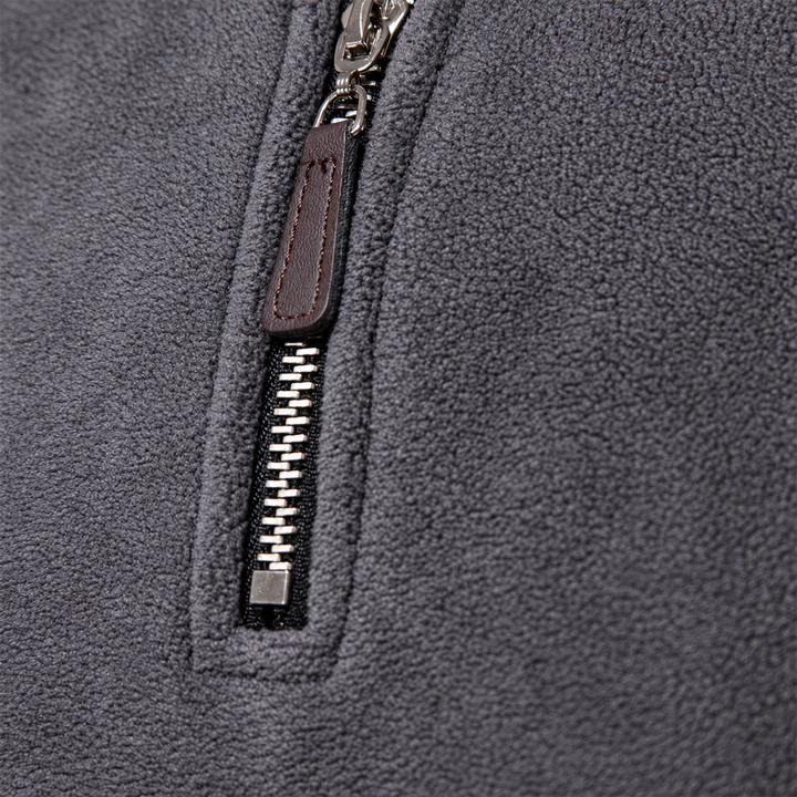 Close-up of the zipper and brown pull tab on the charcoal fleece
