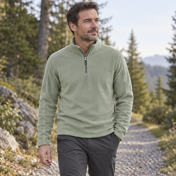 Man hiking in a sage green quarter zip fleece on a gravel forest path
