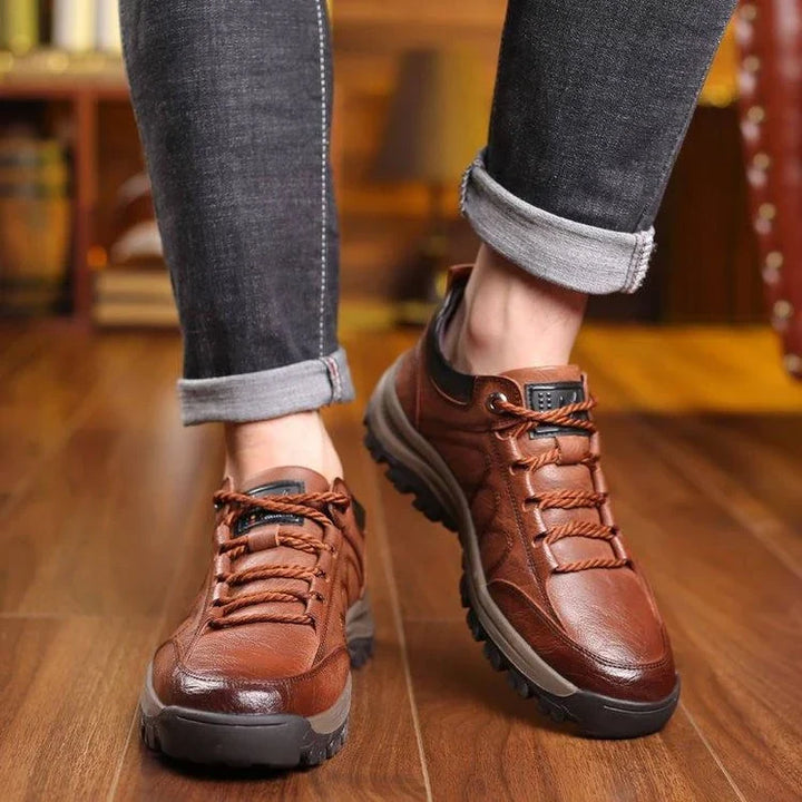 Brown hiking shoes worn with grey jeans on a wooden floor