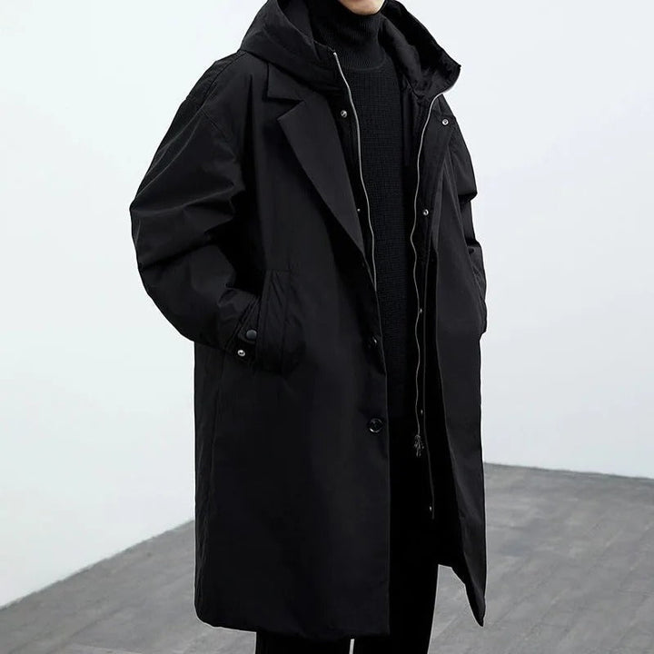 Black hooded trench coat with notch lapel worn over a dark turtleneck