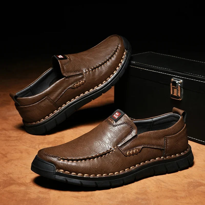 Pair of brown slip on loafers with stitched toe on a dark background