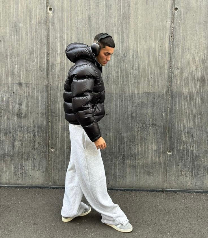 Side view of the black cropped puffer with hood up, paired with light sweatpants