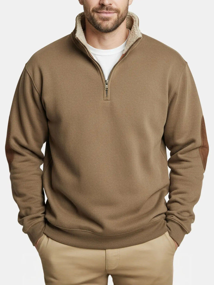 Man wearing the khaki quarter zip sweater with fleece collar, hands in pockets, front view