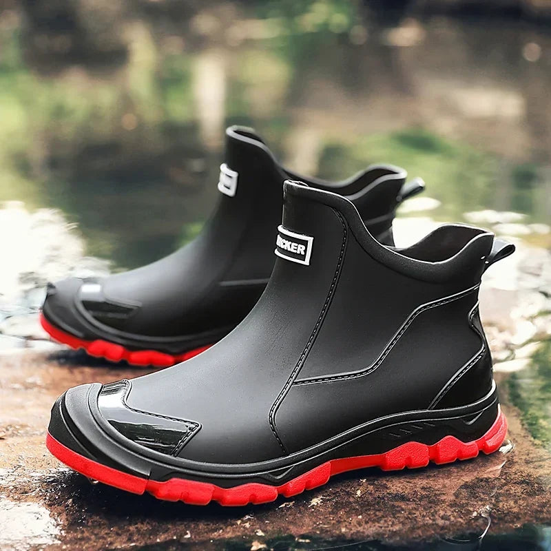 Men's rain boots in black with red lug sole, short pull on, pair by water