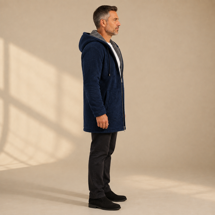 Side profile of a man in the navy longline hooded jacket and black pants